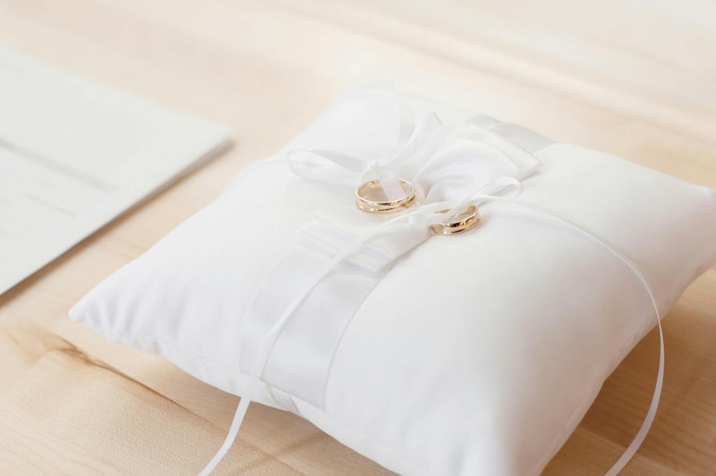 Two gold bands resting on a white pillow.